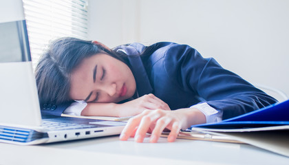 portrait of young asian business woman sleeping  on the desk in weariness