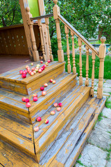 Fresh red apples lie on a wooden painted staircase. The paint was peeling in places. Horizontally.