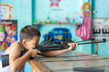 Caucasian teenage boy aiming with pneumatic rifle in shooting galery, side view