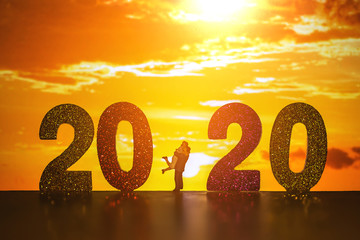 silhouette of miniature couple with text 2020  over blurred sunset background image for Happy new...