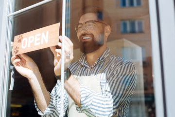 Joyful delighted man putting the sign on the window