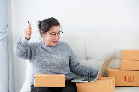 Asian Senior Woman Retirement Using Laptop Computer And Packing Box Selling Online Market Concept