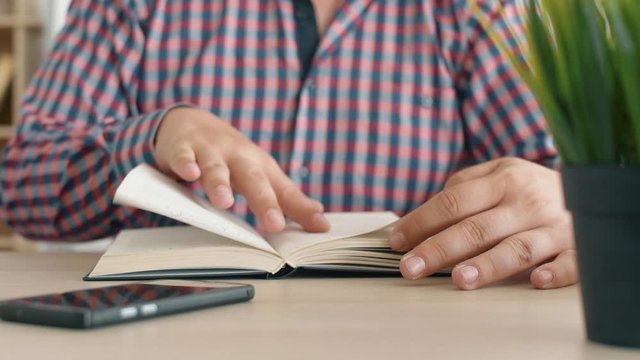 Man read interesting book on office table. Close up 4k slow motion footage.