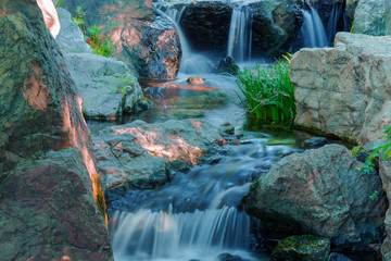 Water falls over a jumble of moss-covered boulders in forest.