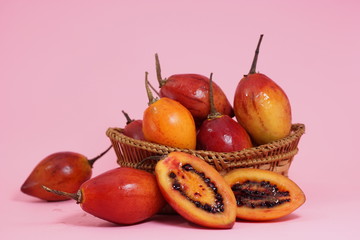 fresh tamarillo fruit on bamboo basket isolated on pink background