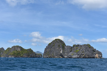 Small rock formations and blue waters and sky.