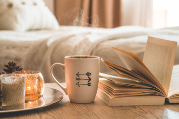 Book, cup of coffee and many candles on the home background.  Home and home decor. Candles flame. HOME concept
