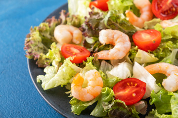 Shrimps salad with tomatoes and mixed greens on a plate.  Healthy food concept