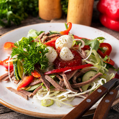 Tasty salad with beef tongue, vegetables and quail eggs.