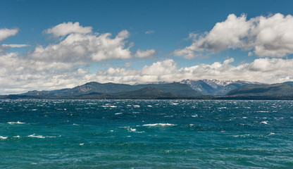 Fototapeta na wymiar Nahuel Huapi lake, San Carlos de Bariloche (Argentina). Waves on the lake. Mountains with fresh snow surrounding the lake.