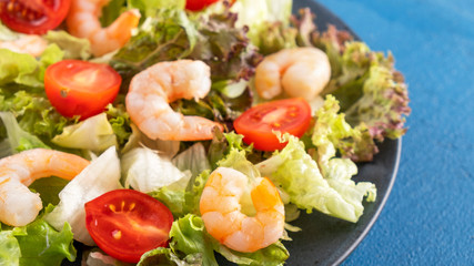 Shrimps salad with tomatoes and mixed greens on a plate. Diet food. Healthy food concept