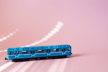 Model of a Russian metro car on a pink background with sunlight. Russian transport. Toy model