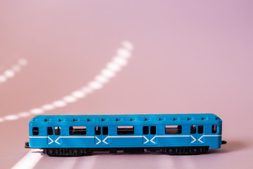 Model of a Russian metro car on a pink background with sunlight. Russian transport. Toy model