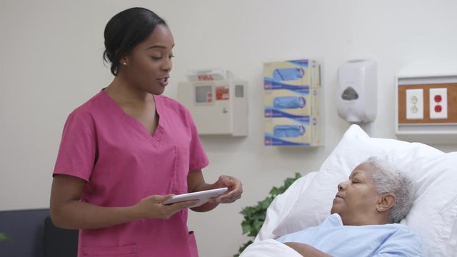 Nurse reviews electronic chart with patient on a tablet in hospital room