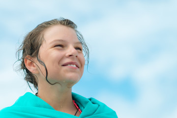 Teenage laughing girl wrapped in a turquoise towel - after swimming in the sea