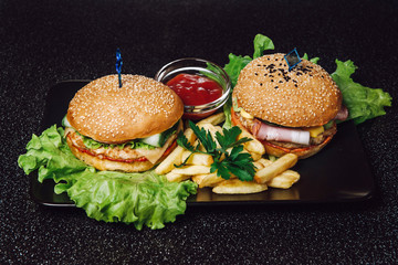 Burgers and french fries fast food on a tray and on a black background