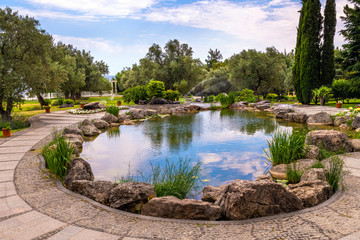 Fragment of beautiful garden with an artificial pond in summer