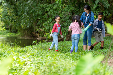 Fototapeta premium Group family asian children collecting garbage and plastic on the river to dumped into the trash for volunteer charity save environment. Ecology earth Concept.