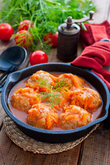 Meatballs with rice in tomato sauce and vegetables in a black cast iron pan, selective focus