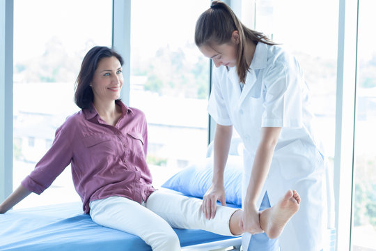 Trained professionals physiotherapist treating senior Caucasian woman in hospital or clinic to reduce pain from injury. Orthopedic doctor checking up patient.Physical therapy help aged people stronger