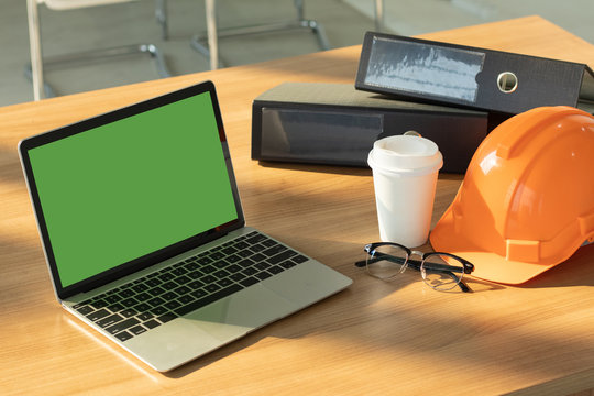 Orange helmet,blank notebook and stationary on office desk. Engineering work relax or creative atmosphere with natural light. Brainstorming or meeting preparation.