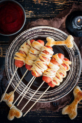 Sausages with mummy dough on a wooden table for Halloween party, top view, selective focus