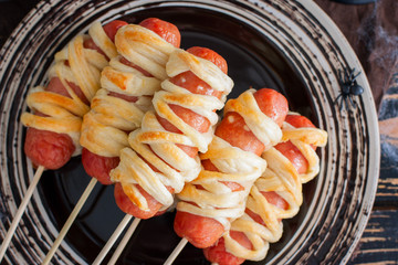 Sausages wrapped in dough in the form of a mummy for decorating a table for the holiday Halloween,...