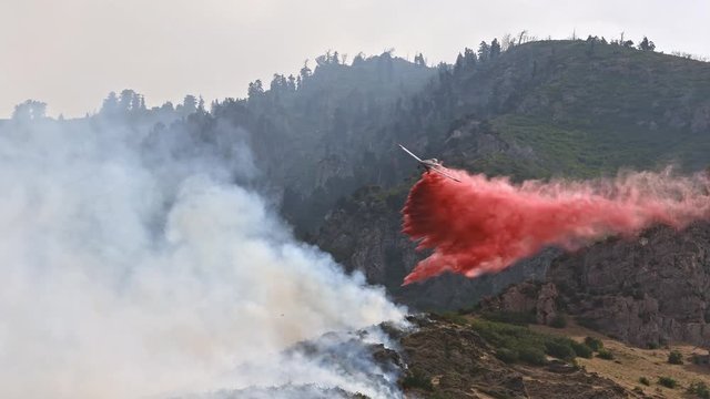 Airplane dropping fire retardant on wildfire burning on mountain above Provo Utah on July 31st, 2019.