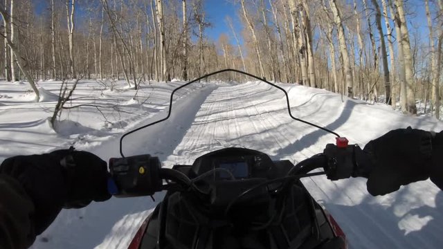 A person rides a snowmobile on a mountain road