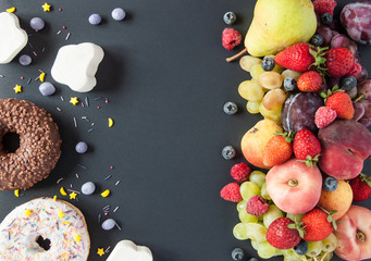 A lot of natural and healthy vitamin fruits, berries vs sweet and junk food on a black background....