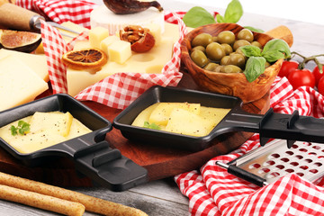 Delicious traditional Swiss melted raclette cheese on diced boiled or baked potato and baguette served in individual skillets with salami..