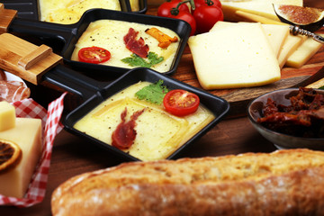 Delicious traditional Swiss melted raclette cheese on diced boiled or baked potato and baguette served in individual skillets with salami..