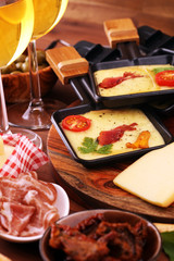 Delicious traditional Swiss melted raclette cheese on diced boiled or baked potato and baguette served in individual skillets with salami..