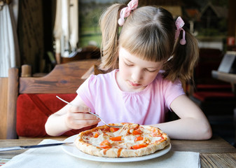 Serious little girl eats pizza