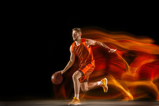The comet. Young caucasian basketball player of red team in action and motion in mixed light over dark studio background. Concept of sport, movement, energy and dynamic, healthy lifestyle. © master1305