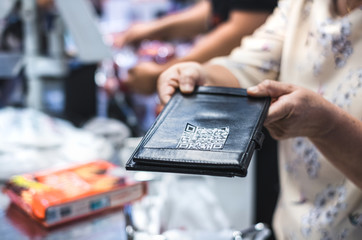 Seller or trader handing QR code to customer for moibile online payment. Qr code payment , online shopping , cashless technology concept.
