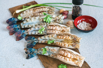 Raw peeled big prawn on wooden cutting board with ingredients.