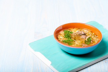Homemade soup with noodles and meatballs on a wooden table. Traditional rural dinner