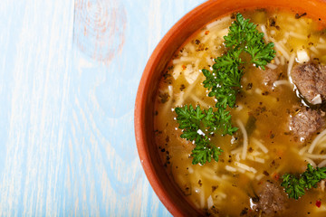 Homemade soup with noodles and meatballs on a wooden table. Traditional rural dinner