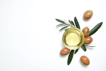 Bunch of local produce Turkish green gemlik olives with glass cup of extra virgin golden oil and olea europaea tree leaves. Close up, top view, copy space, isolated white background.