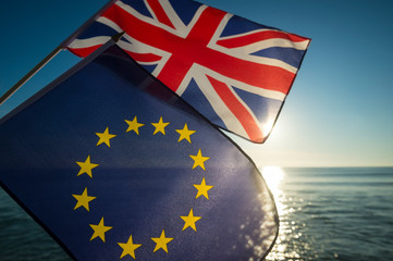 European Union and British Union Jack flags flying together as the sun rises on a new era on the relationship between the EU and the UK after Brexit