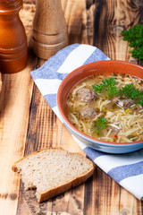 Homemade soup with noodles and meatballs on a wooden table. Traditional rural dinner