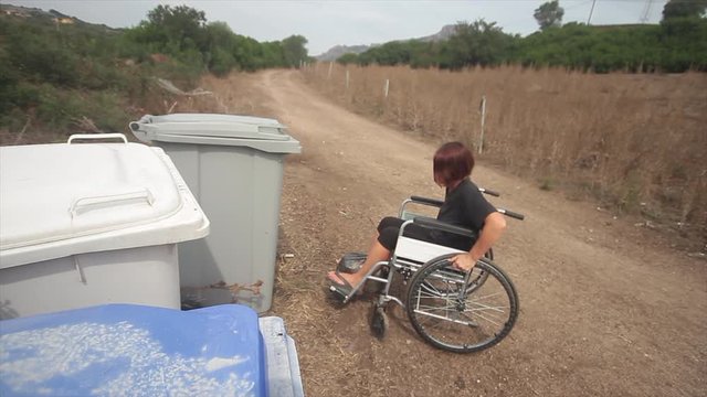 disabled girl in wheel chair in everyday life doing recycling