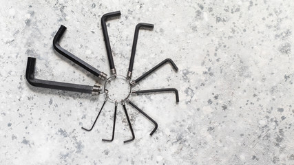 Hand-held mechanical tool hex wrench key L full set of black on a gray concrete background with copy space