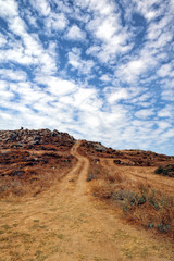 Winding country dirt road leading to a cloudscape, Naxos, Greek Islands