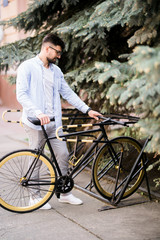 business, lifestyle, transport and people concept. Young man parking bicycle on city street