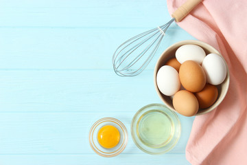 chicken eggs and a whisk on the table top view.