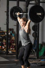 Fototapeta na wymiar Strong young woman powerlifting with heavy weights in gym