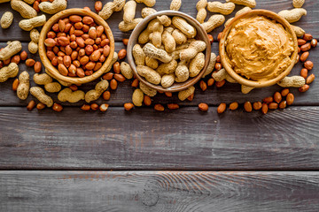 Product for hearty breakfast with peanut butter in bowl near nuts on wooden background top view mockup