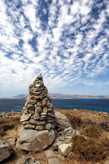 Cairn of rocks and cloudscape at Agios Prokopios, Naxos, looking over blue Aegean Sea to Paros, Greek Islands